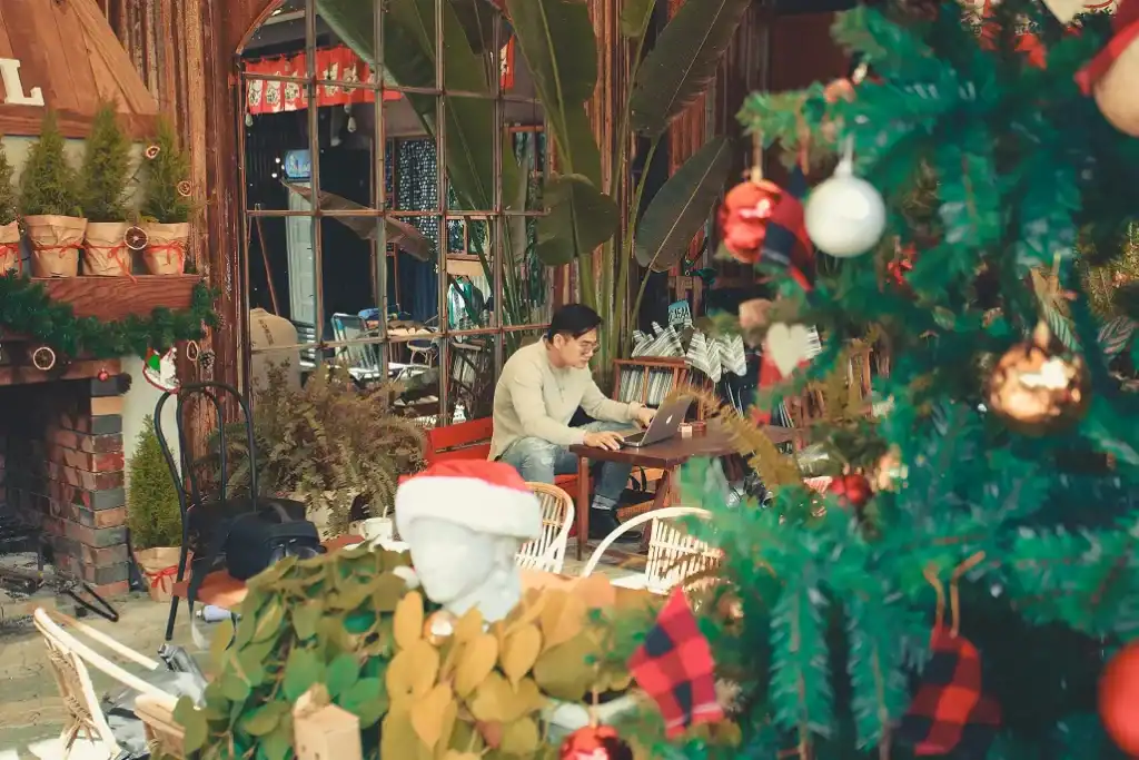 Man working on a laptop with a festive setup surrounding him