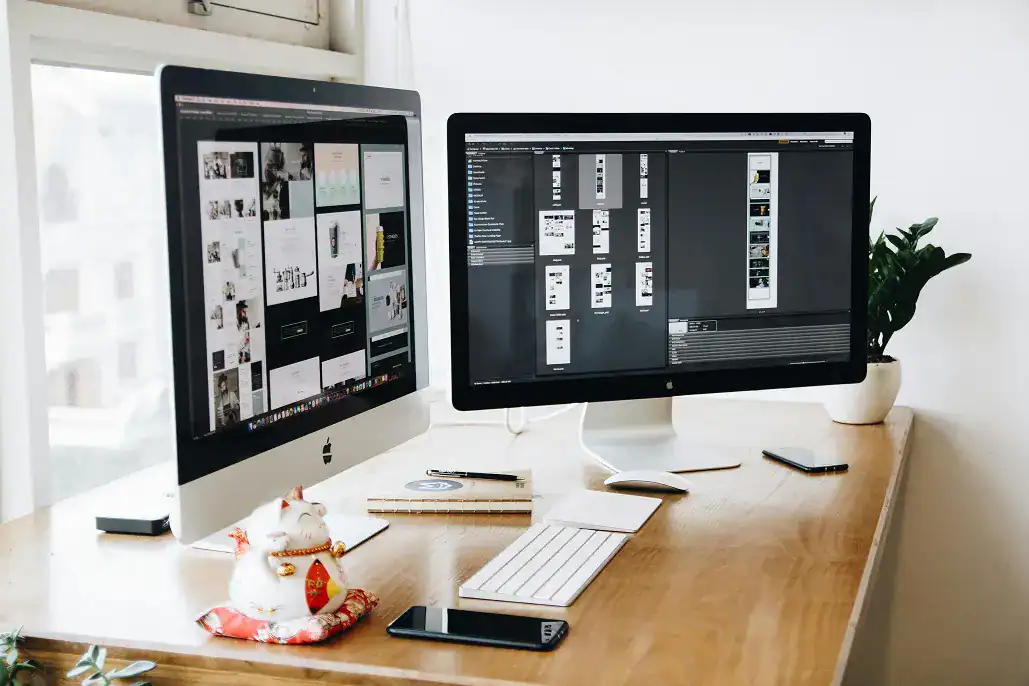 Two desktop screens and a keyboard on an office desk