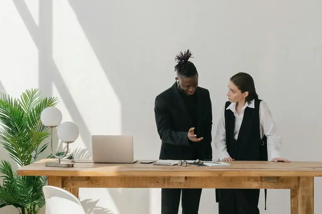 Man and woman standing at a desk in an office setting discussing work